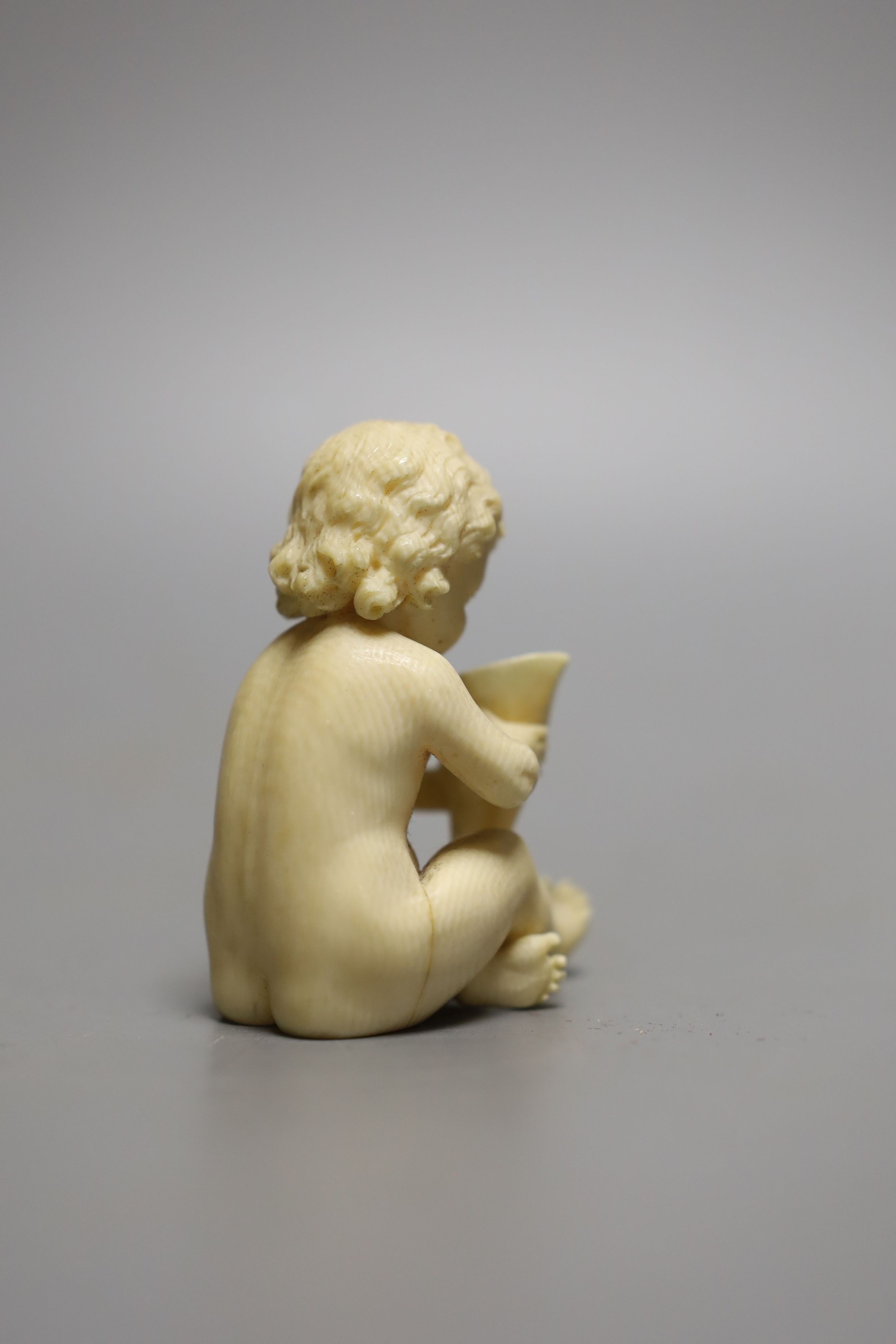 A 19th century Continental carved ivory figure of a child holding a cornucopia - 7cm tall